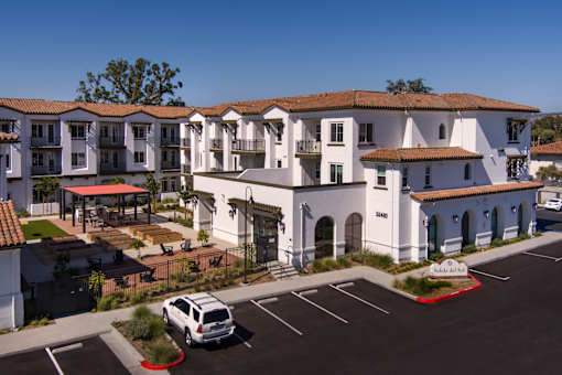 A white building with a red roof and a parking lot in front.