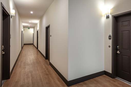 A long hallway with doors on both sides and lights on the ceiling.