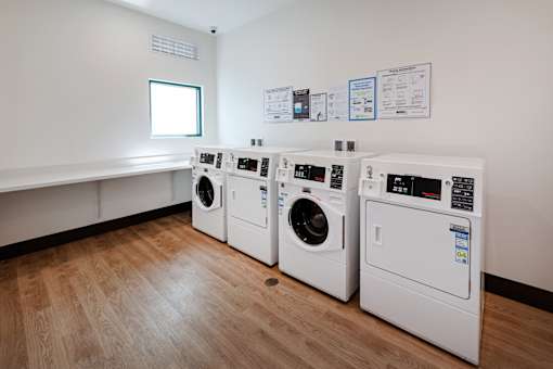Three washing machines are lined up in a laundry room.