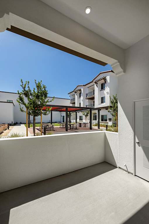 A white building with a balcony overlooking a courtyard.