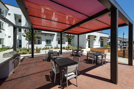 A patio with a table and chairs is covered by a red awning.