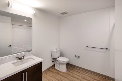 A white bathroom with a toilet, sink, and mirror.