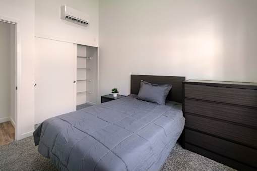 A bed with a grey comforter and a pillow is in the room.