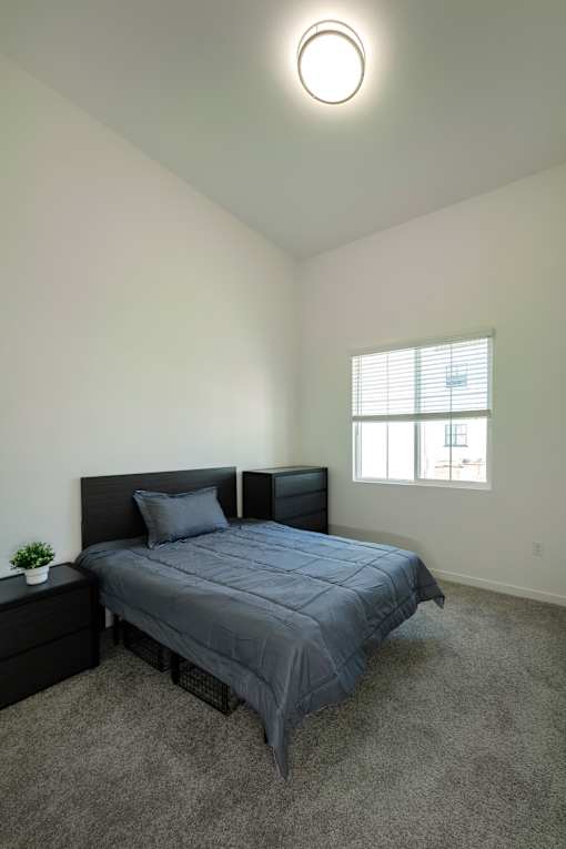 A bedroom with a bed, nightstand, and window.