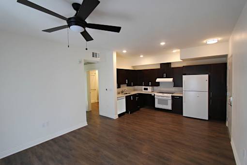 A modern kitchen with white appliances and dark wood floors.