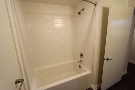 A white tiled bathroom with a bathtub and shower.
