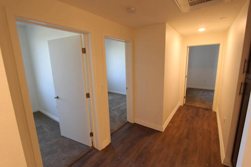 A hallway with three doors and a carpeted floor.