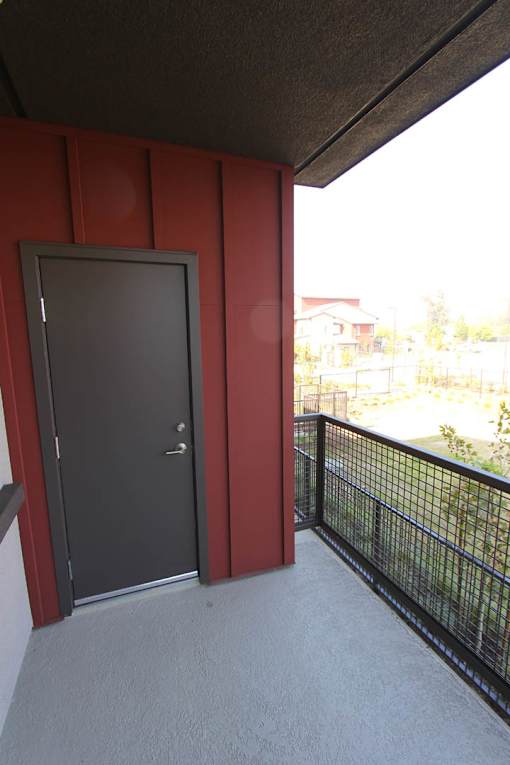 A grey door is on the left side of a red wall.