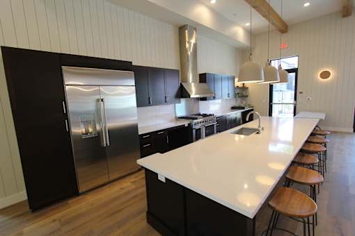 A modern kitchen with a long white island and dark wood cabinets.