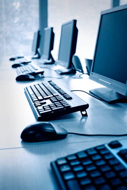 A row of computer monitors are lined up on a desk.