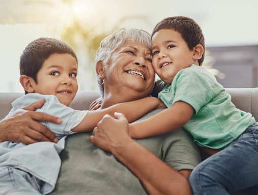 An elderly woman is hugged by two young children.
