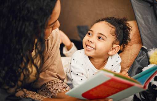 A woman and a child are reading a book together.