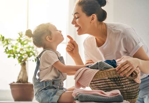 A woman and a child are sitting together, with the woman holding a basket of clothes.