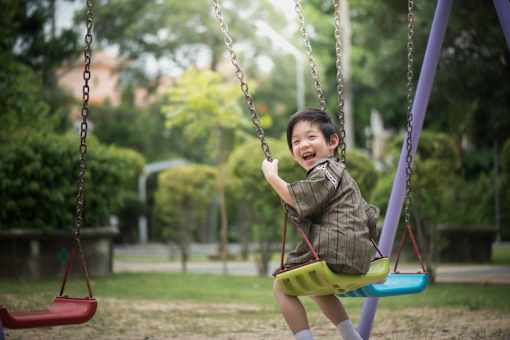 A young boy is swinging on a swing in a park.