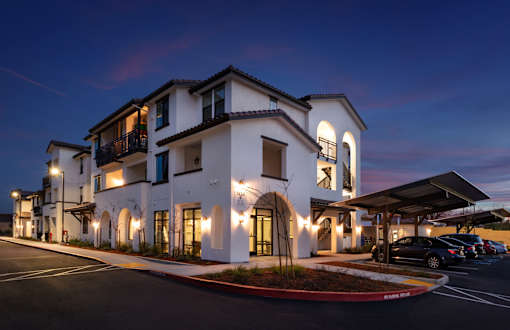 A white building with a black car parked in front.