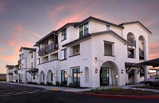 A row of white buildings with balconies and arched windows.