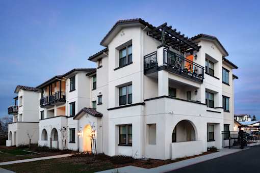 A modern white two-story building with balconies and arched windows.