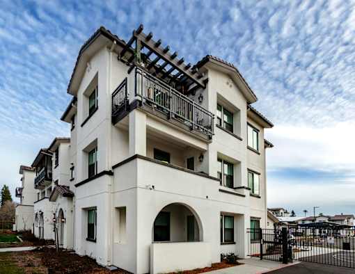 A white two-story house with a balcony on the second floor.