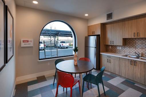 A kitchen with a round table and chairs with a window in the background.