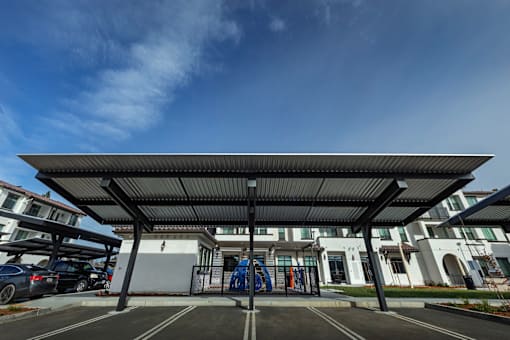A parking lot with a building in the background and a blue sky above.