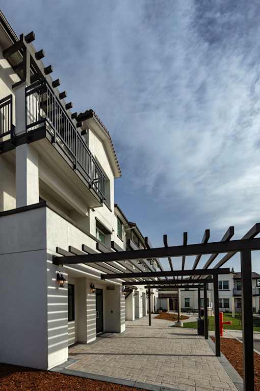 A modern building with a white facade and a black pergola.