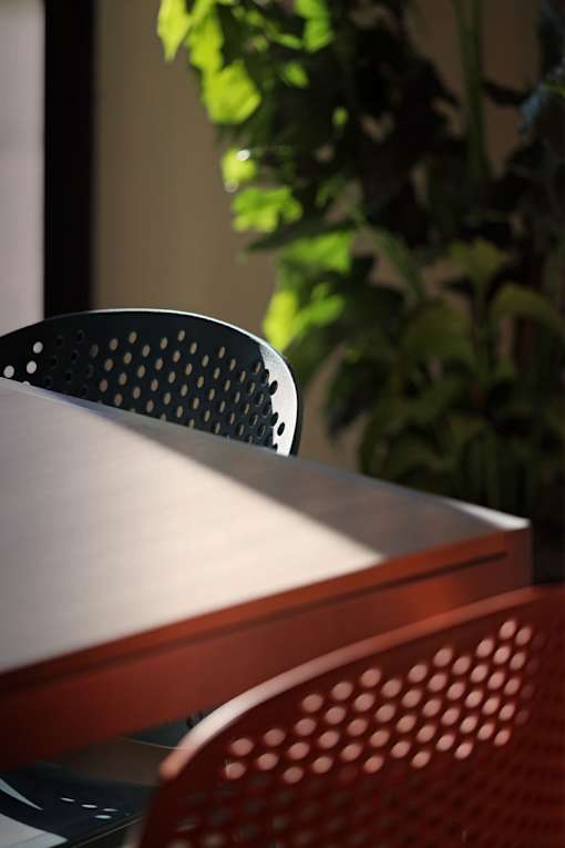 A red chair with a perforated back sits in front of a table.