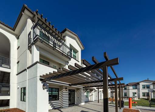 A white building with a black roof and a wooden pergola.