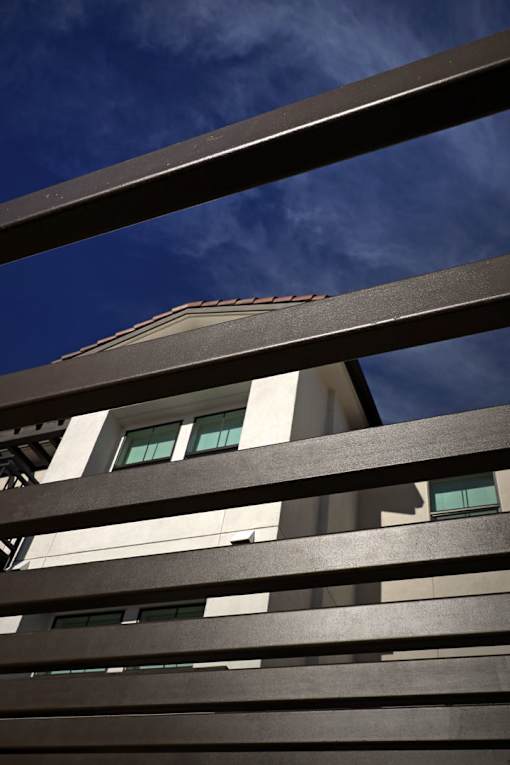 A building with a white facade and dark brown slats in the foreground.