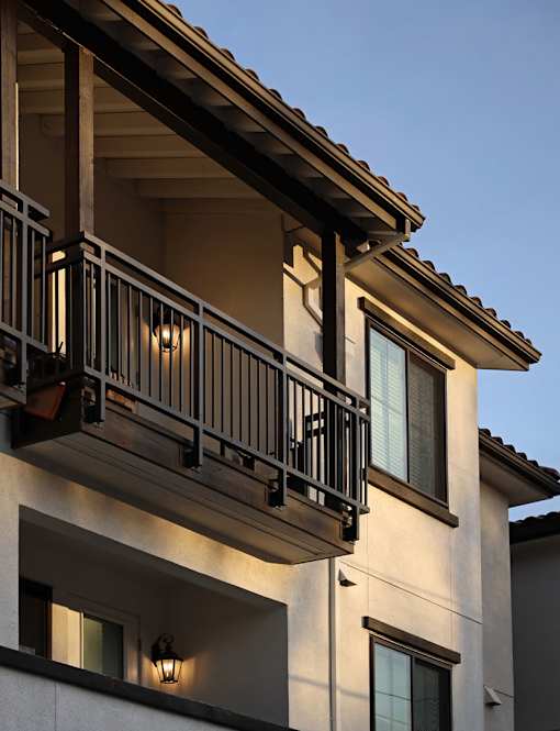 A balcony with a railing and lights is on the second floor of a building.