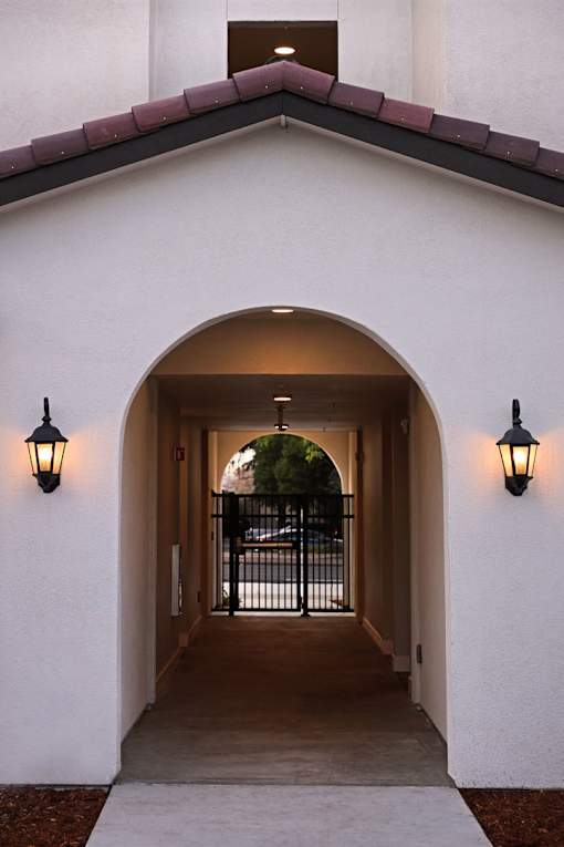A white building with a black gate in the middle of a passage.