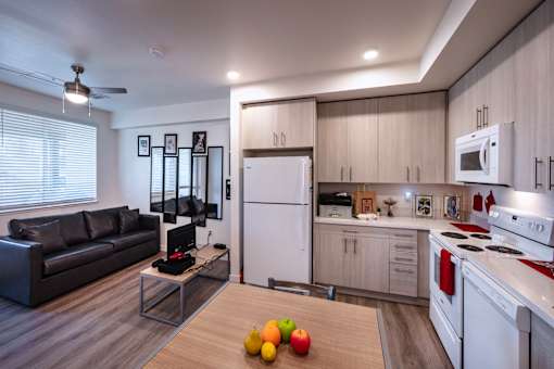 A modern kitchen with a black couch and a wooden table with an apple and two lemons on it.