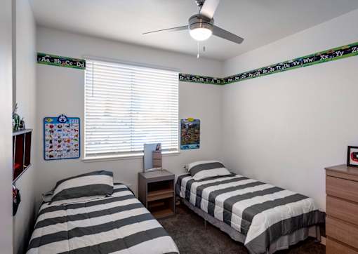 A bedroom with two beds and a ceiling fan.