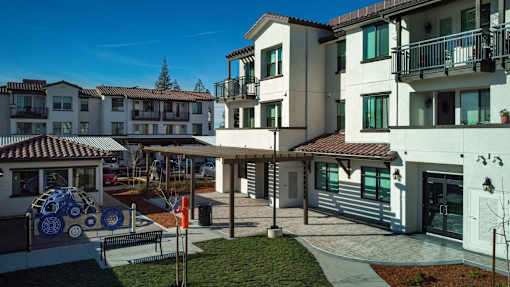 A sunny day at a courtyard with a white building and a small gazebo.