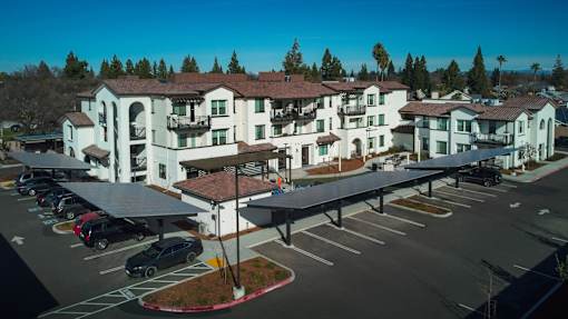 A large white building with a red roof and a parking lot in front.
