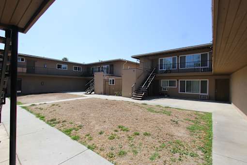 A brown house with a brown fence and a brown lawn.