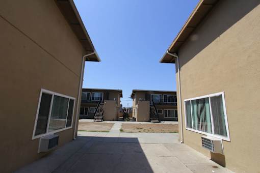A view of a courtyard between two buildings with a clear blue sky above.