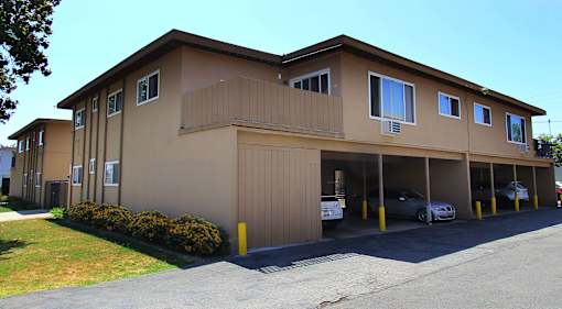 A brown building with a parking lot in front.