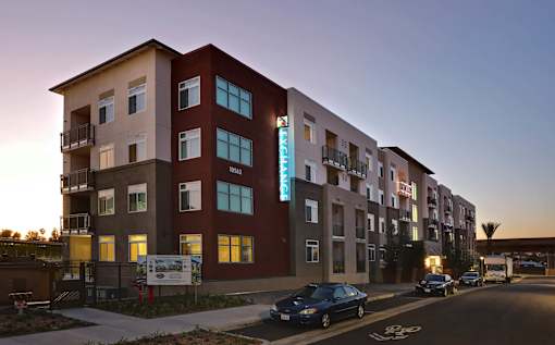 A modern apartment building with a car parked in front.