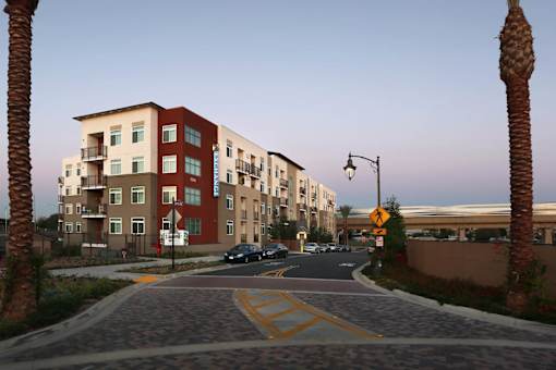 A street view of a residential area with apartment buildings and palm trees.