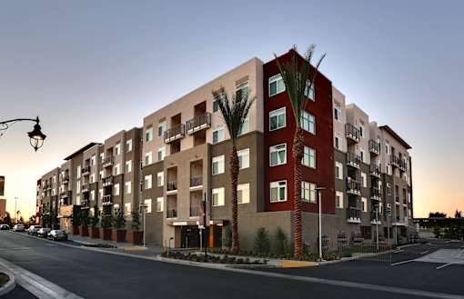 A modern apartment building with palm trees in front.
