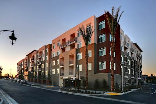 A modern apartment building with palm trees in front.