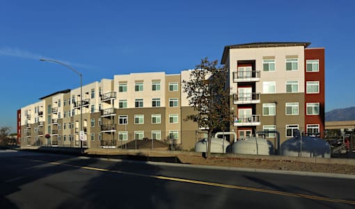 Apartment buildings on a street corner with a clear blue sky.