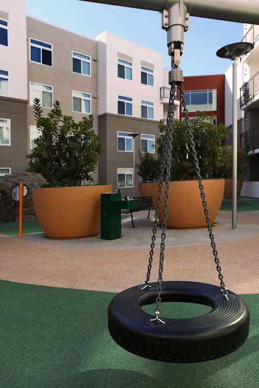 A tire swing hangs from a metal pole in a playground.