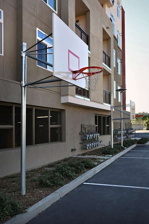 A basketball hoop is attached to a pole in front of a building.