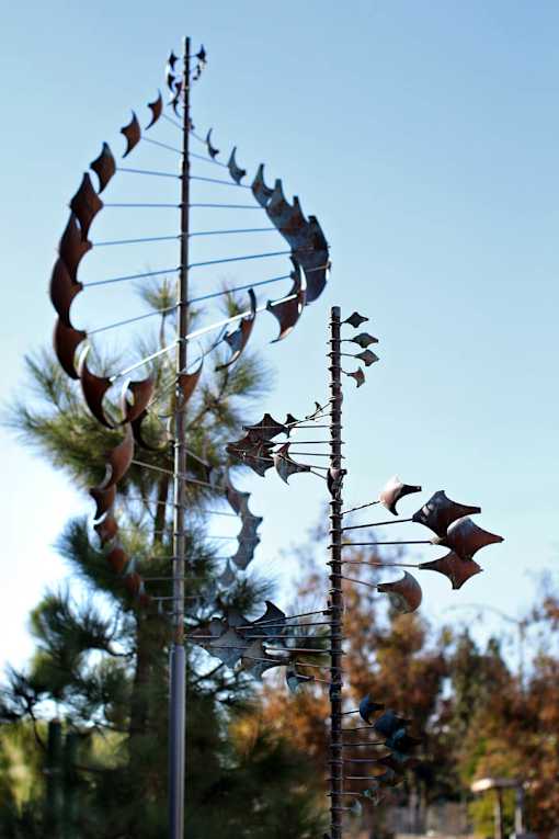 A wind vane with a dragon design is shown against a blue sky.
