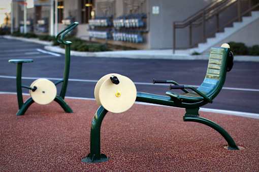Two exercise benches with weights on them are in the foreground of a street.