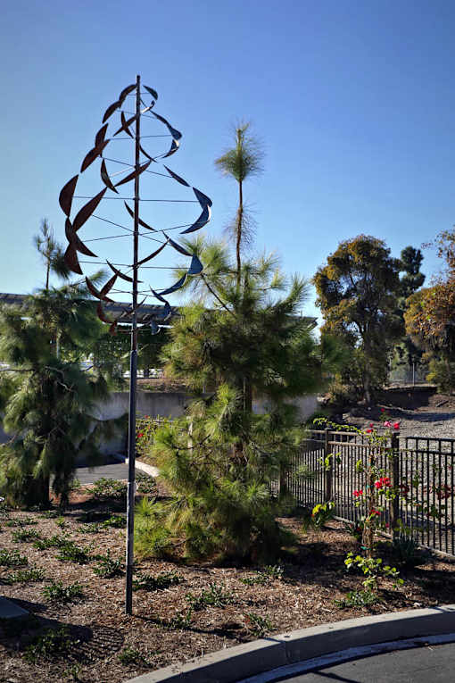 A metal sculpture of a tree stands in a garden.