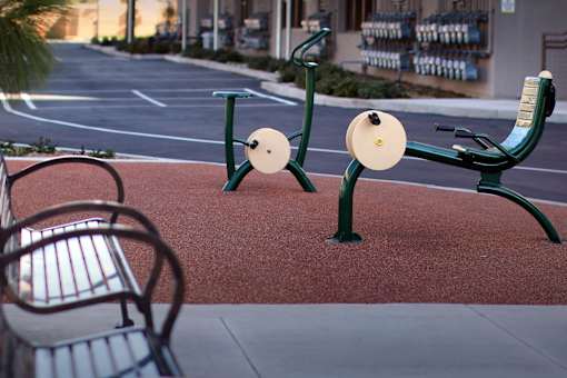 Two green exercise bikes are on a red brick walkway.