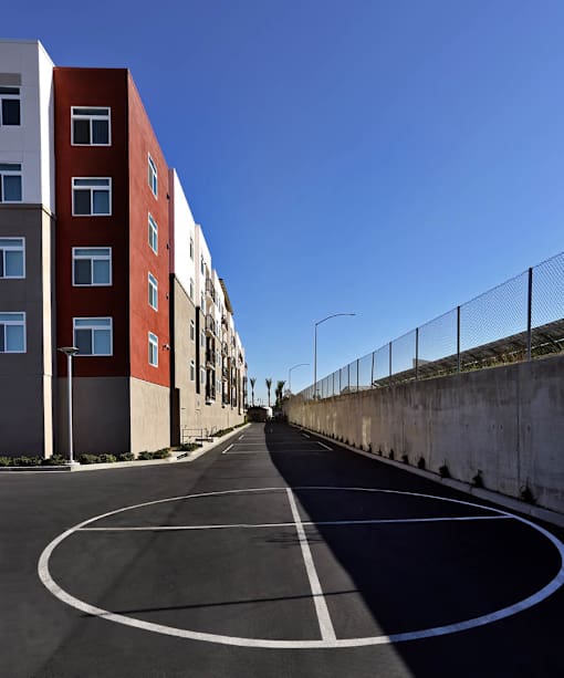 A curved road is lined with apartment buildings and a fence.