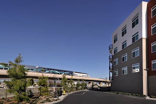 A train is passing over a road next to a tall building.